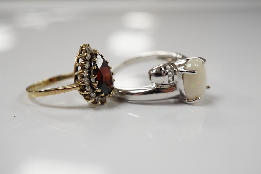 A modern 9ct white gold and single stone cabochon white opal set ring, size N and a 9ct gold, garnet and white sapphire? cluster ring, gross weight 6.7 grams. Condition - fair to good